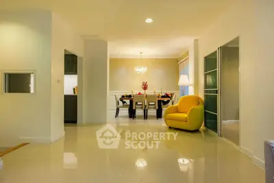 Elegant open-plan living and dining area with modern decor and bright yellow armchair.