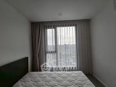 Minimalist bedroom with large window and sheer curtains offering city view
