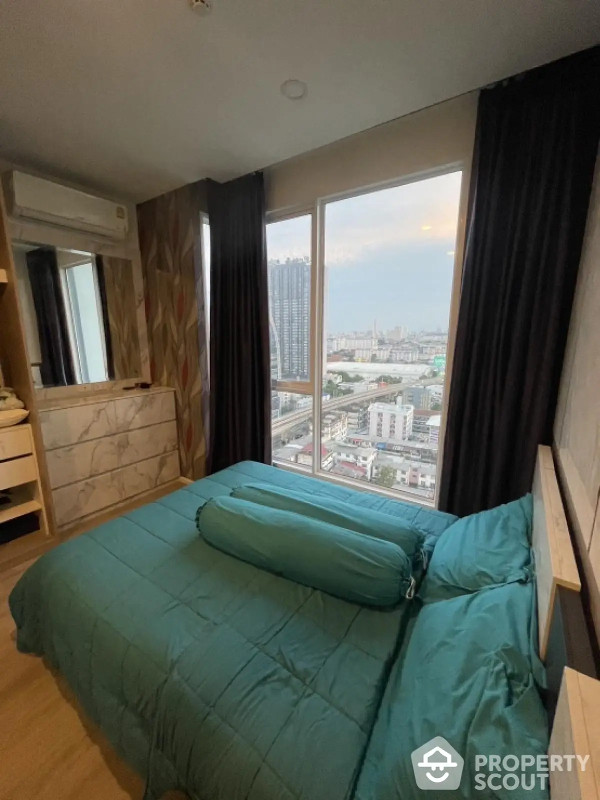 Modern bedroom with city view, featuring stylish decor and large windows for natural light.