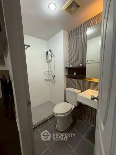 Modern bathroom with sleek design, featuring a shower, toilet, and stylish sink area.