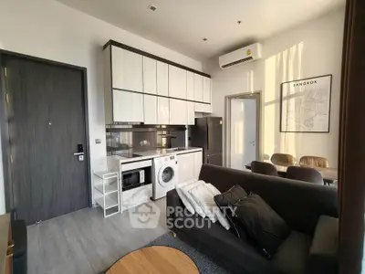 Modern living room with integrated kitchen featuring sleek appliances and stylish decor in a Bangkok apartment.