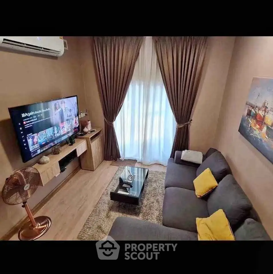 Cozy living room with modern decor, large TV, and plush sofa in a stylish apartment.