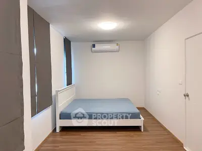 Minimalist bedroom with wooden flooring and air conditioning