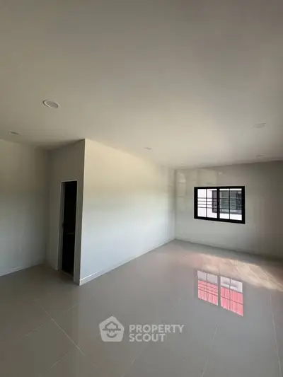 Spacious empty room with glossy tiled floor and large window, perfect for customization.