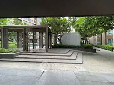 Modern apartment complex entrance with landscaped garden and stylish architecture.