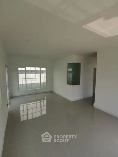 Spacious empty room with large windows and glossy tiled floor, perfect for customization.