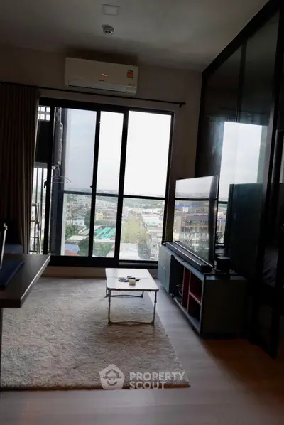 Modern living room with large window offering stunning city view, sleek furniture, and cozy ambiance.