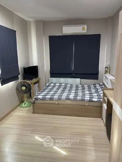 Cozy bedroom with modern decor, featuring a comfortable bed, air conditioning, and stylish wooden flooring.