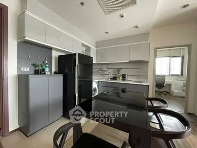 Modern kitchen with sleek cabinetry, black appliances, and dining area in contemporary apartment.