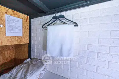 Cozy bedroom with white brick wall and hanging towel, perfect for minimalist living.