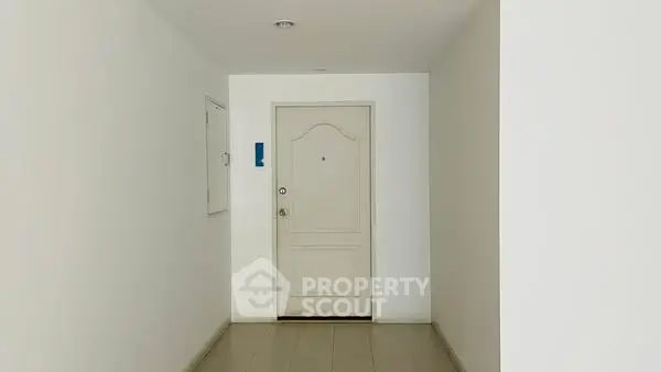 Minimalist apartment entrance with white door and tiled floor