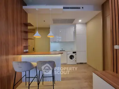 Modern kitchen with sleek design, featuring a washing machine and stylish bar seating.