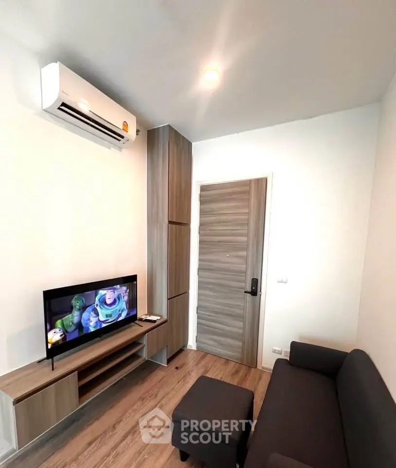 Modern living room with sleek furniture and wall-mounted TV, featuring a cozy atmosphere and efficient use of space.