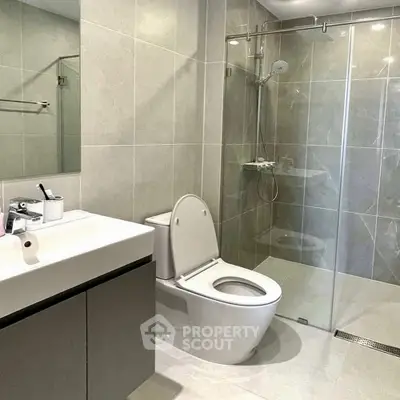 Modern bathroom with glass shower and sleek fixtures in contemporary design.