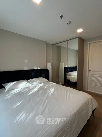 Modern bedroom with mirrored wardrobe and cozy bedding in a stylish apartment.