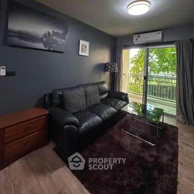 Cozy living room with black leather sofa and balcony view