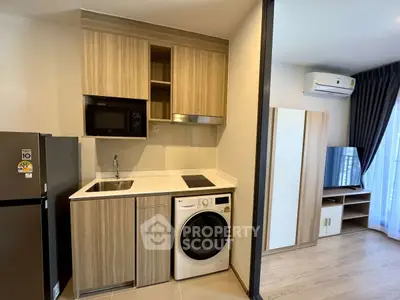 Modern compact kitchen with washing machine and microwave in stylish apartment.