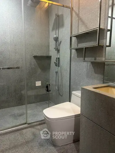 Modern bathroom with sleek design, featuring a glass shower enclosure and contemporary fixtures.