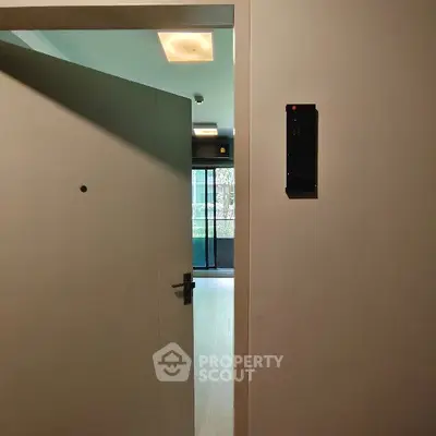 Modern apartment entrance with open door leading to bright living space.