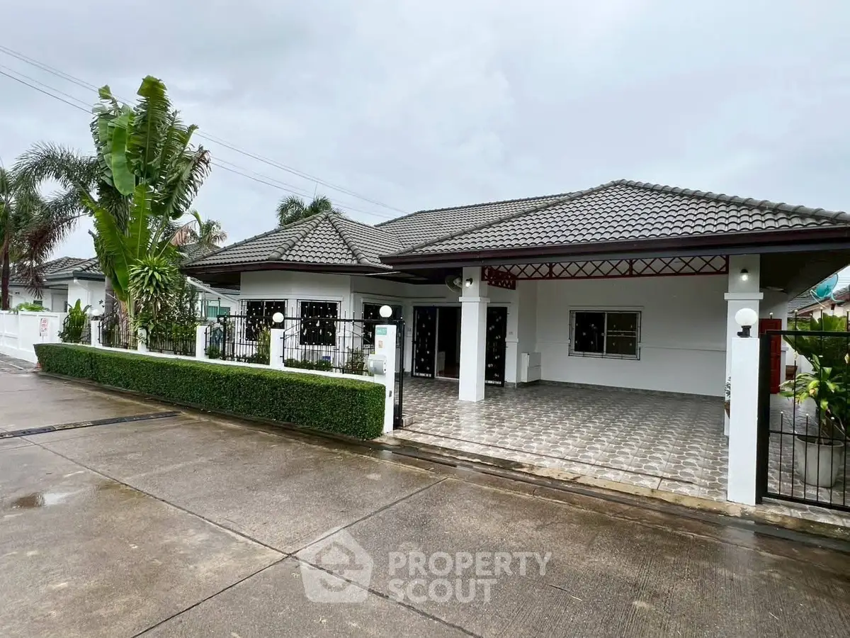 Charming single-story house with tiled roof and lush greenery in a serene neighborhood.