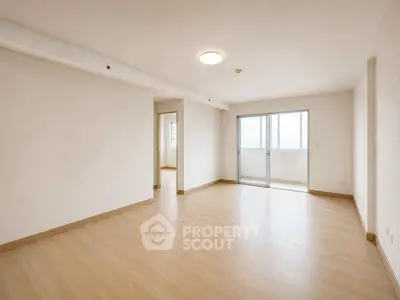 Spacious unfurnished living room with wooden flooring and large windows for natural light.
