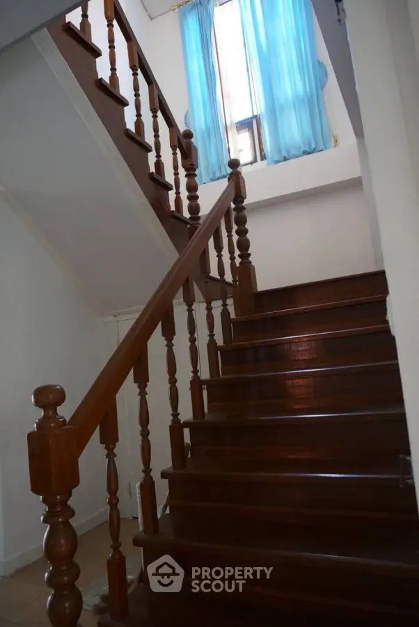 Elegant wooden staircase with blue curtains in a bright home interior