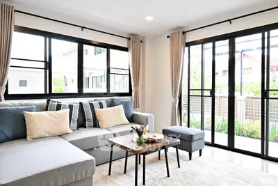 Modern living room with large windows and stylish furniture, offering a bright and inviting atmosphere.