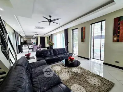 Luxurious modern living room with sleek black leather sofas and elegant decor in a spacious open layout.