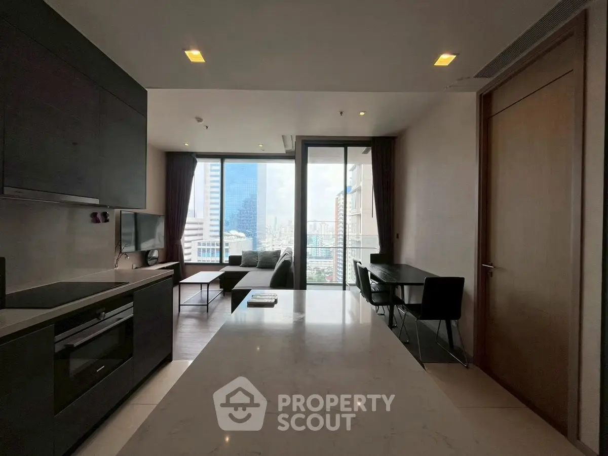 Modern living room with city view, open kitchen, and sleek furniture in a high-rise apartment.