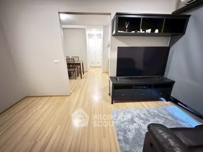 Modern living room with sleek wooden flooring and stylish black TV stand.