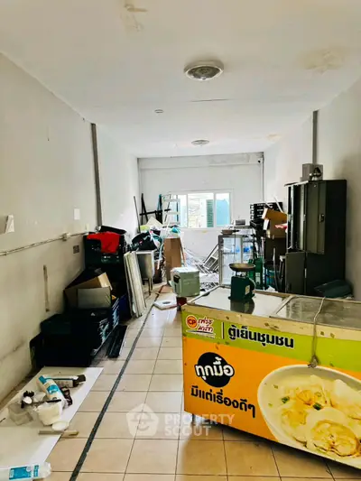 Spacious storage area with potential for renovation, featuring tiled flooring and ample natural light.
