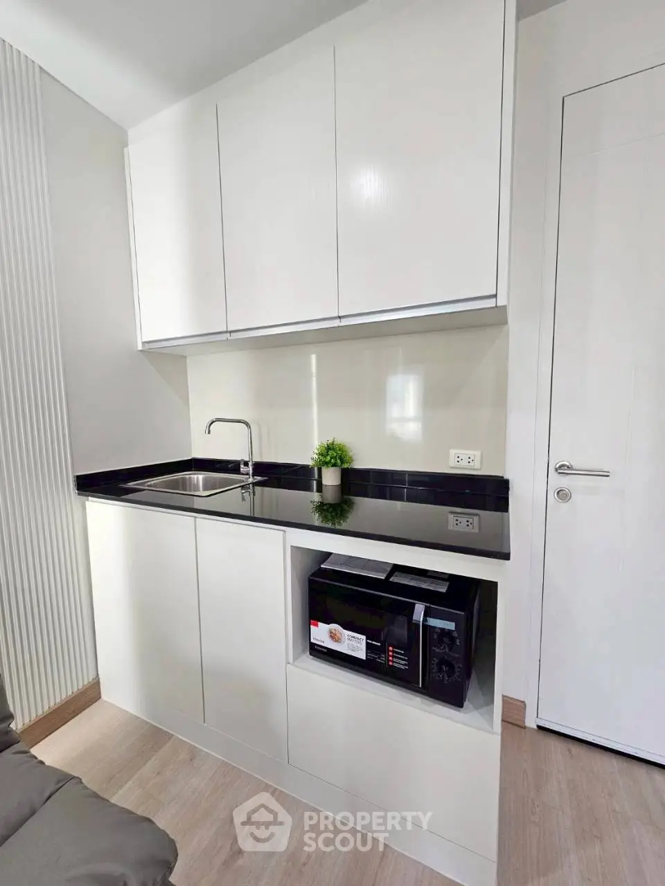 Modern compact kitchen with sleek white cabinets and built-in microwave