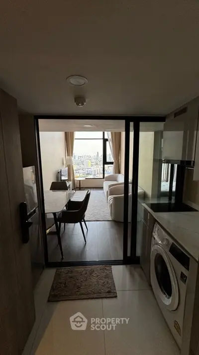 Modern apartment with open kitchen and city view, featuring a washing machine and cozy living area.
