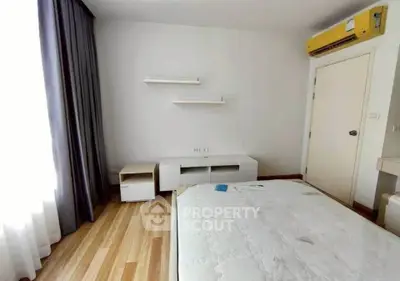 Spacious bedroom with natural light and modern furnishings in a stylish apartment.