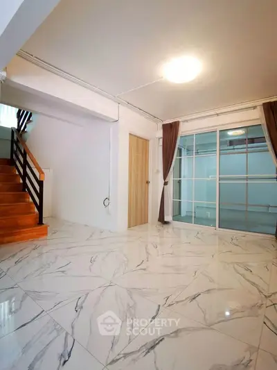 Spacious modern living room with marble flooring and wooden staircase