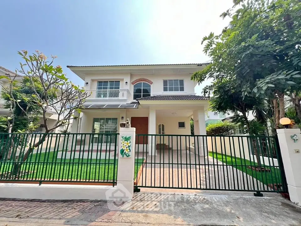 Charming two-story house with lush garden and secure gated entrance.