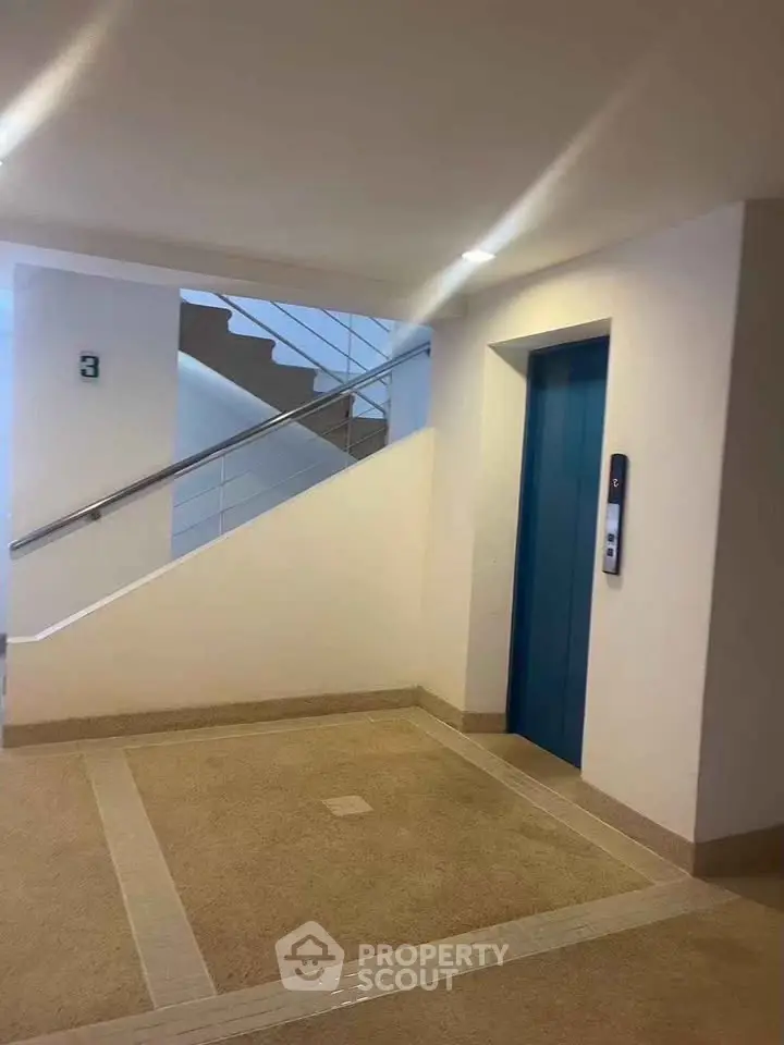 Modern building interior with elevator and staircase, showcasing clean design and accessibility.