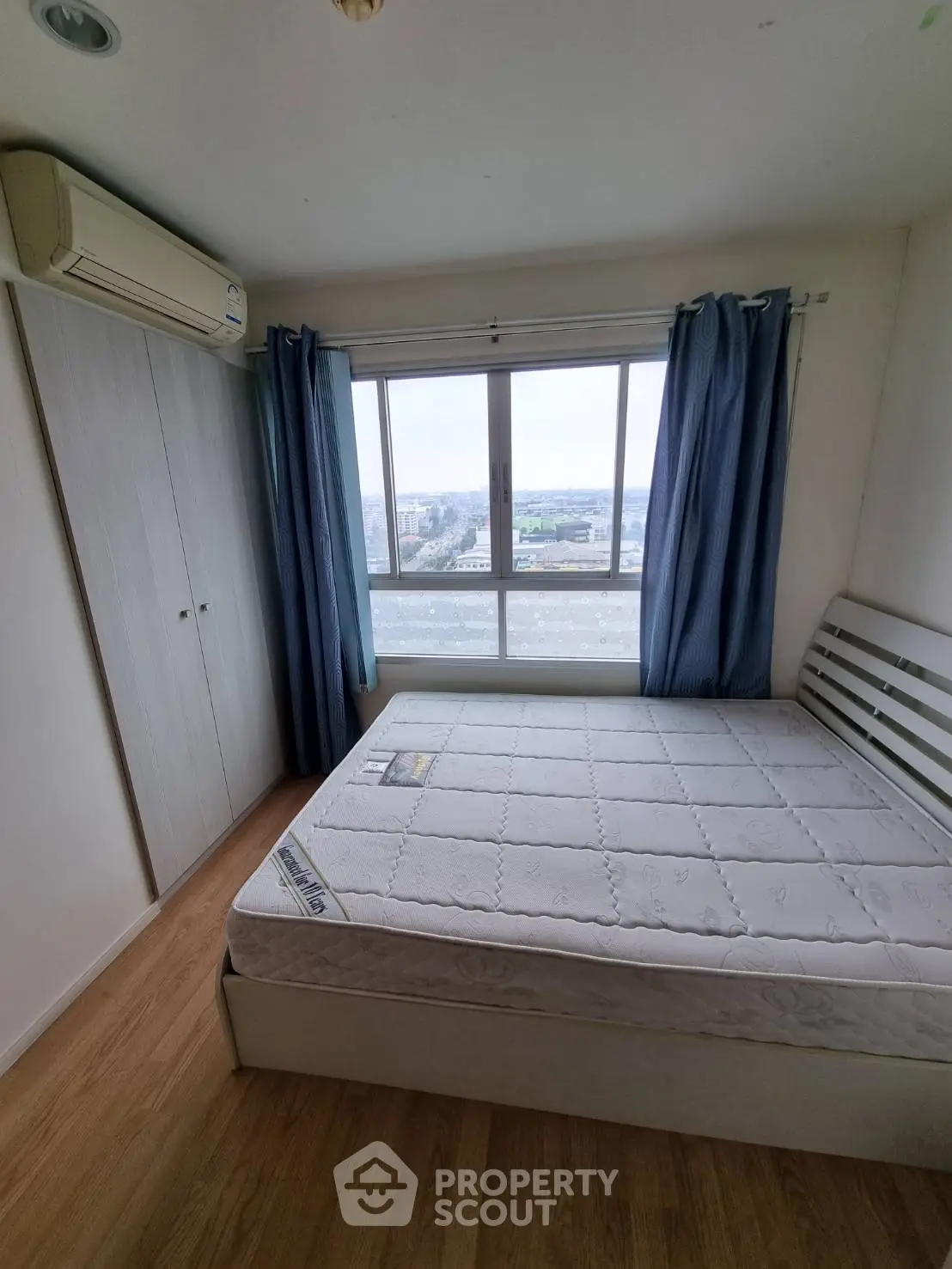 Cozy bedroom with large window and city view, featuring a comfortable bed and ample closet space.