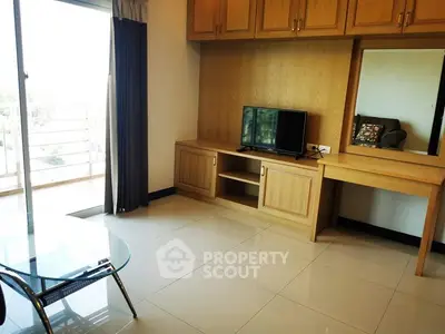 Bright living room with wooden cabinets and glass table, featuring a balcony view.