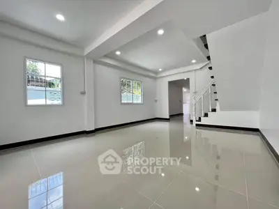 Spacious modern living room with glossy tiled floors and staircase, perfect for family gatherings.