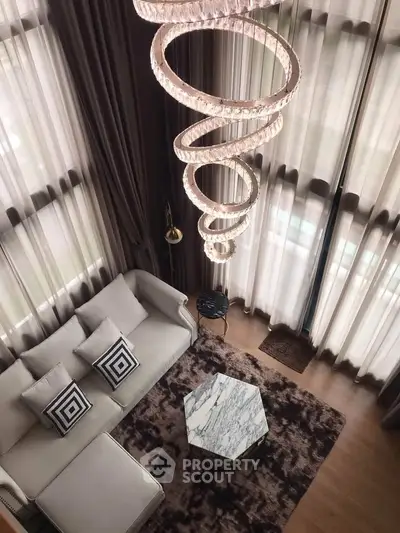 Luxurious living room with high ceilings, elegant chandelier, and stylish decor