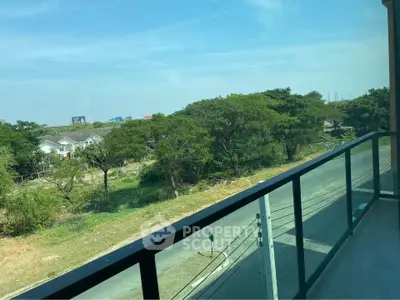 Spacious balcony with scenic view of lush greenery and clear blue sky.