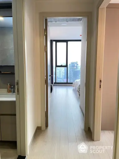 Inviting modern bedroom with a view, featuring light wood flooring and a glimpse of the cityscape through floor-to-ceiling windows.