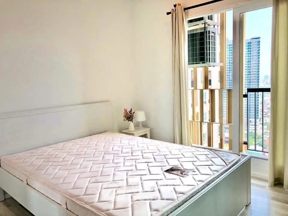 Bright bedroom with large window and city view, featuring a comfortable bed and modern decor.