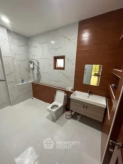 Luxurious modern bathroom with elegant marble and wood finishes, featuring a sleek vanity and spacious shower area.