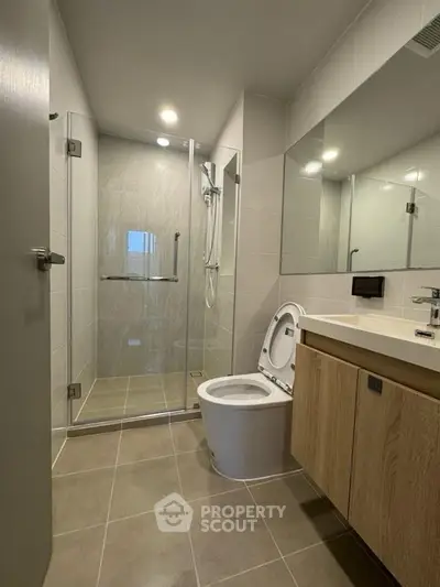 Modern bathroom with glass shower and sleek fixtures in contemporary apartment.