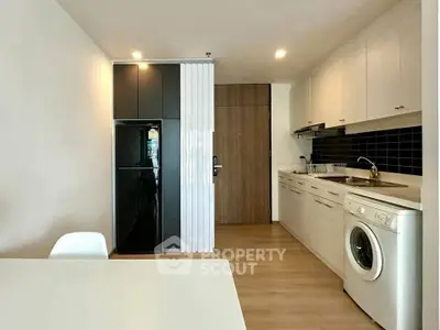 Modern kitchen with sleek appliances and washing machine in stylish apartment.