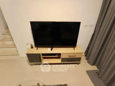 Modern living room with sleek TV stand and large flat-screen TV, perfect for entertainment.