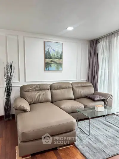 Modern living room with stylish leather sofa and glass coffee table, featuring elegant decor and natural light.