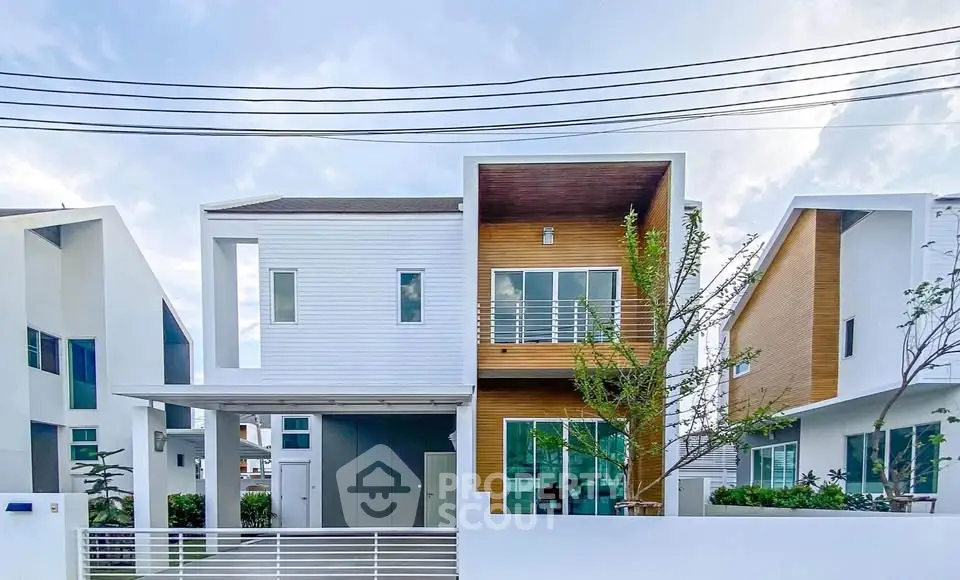 Modern two-story house with sleek design and large windows in a suburban neighborhood.